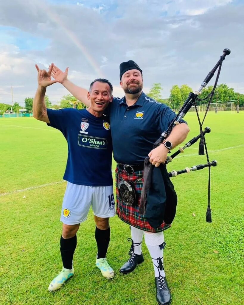 bagpiper and football player on a field in Bangkok Thailand