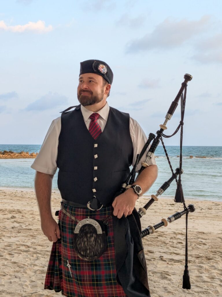 Bagpiper standing on the beach holding bagpipes during a wedding on Koh Samui. 